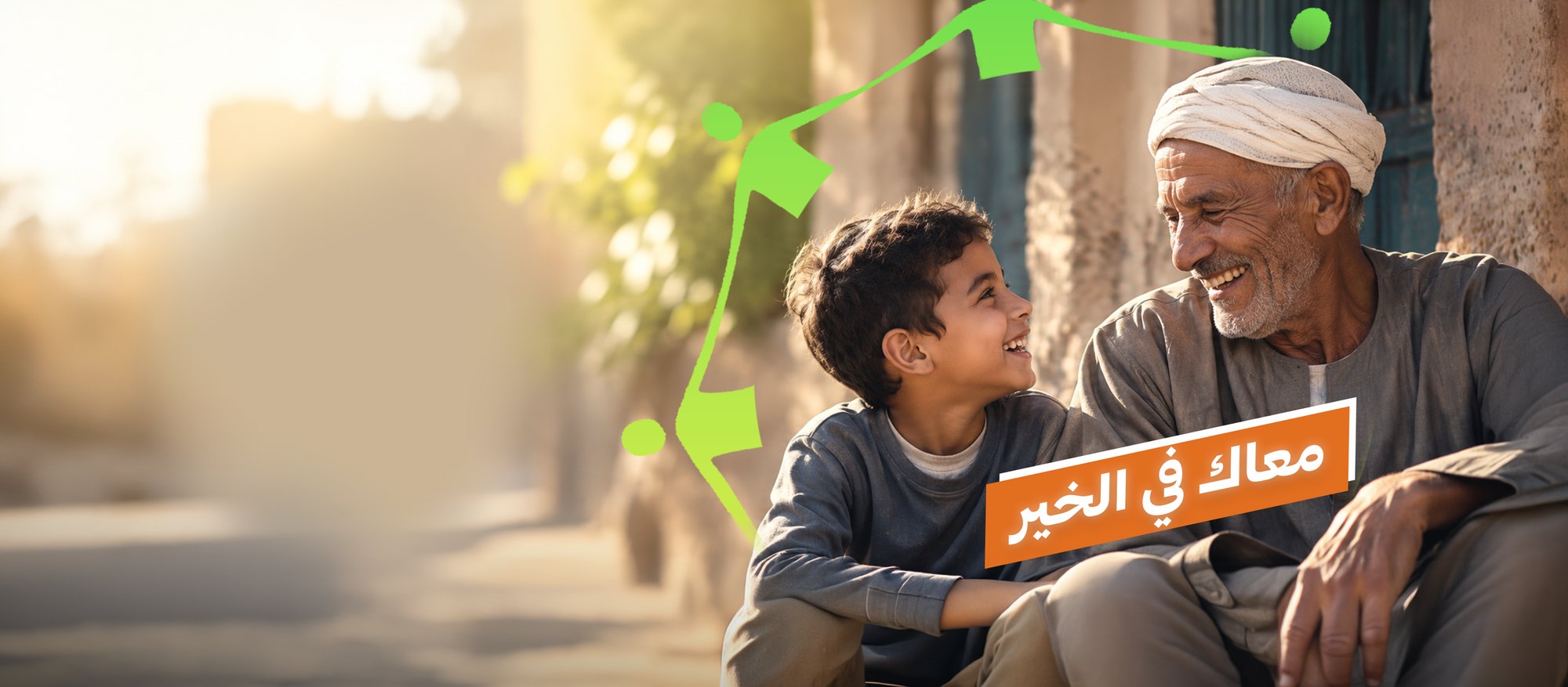 جد مصري وحفيده يتبادلان الضحك أمام بيت ريفي، مع شعار معاك في الخير